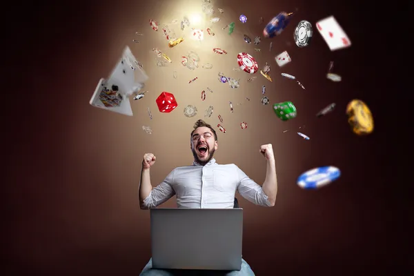 CD444 Games — Discover modern slots and table adventures A man celebrating a winning moment on his laptop while gaming symbols float around him, capturing the excitement of CD444 games.